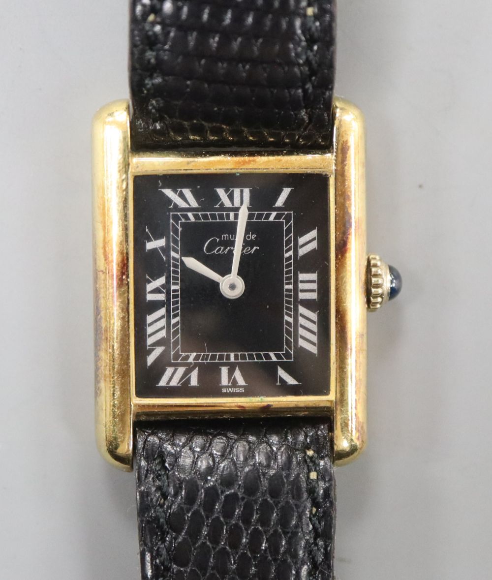 A ladys 925 gilt Must De Cartier manual wind wrist watch, with rectangular black Roman dial, on Cartier strap,